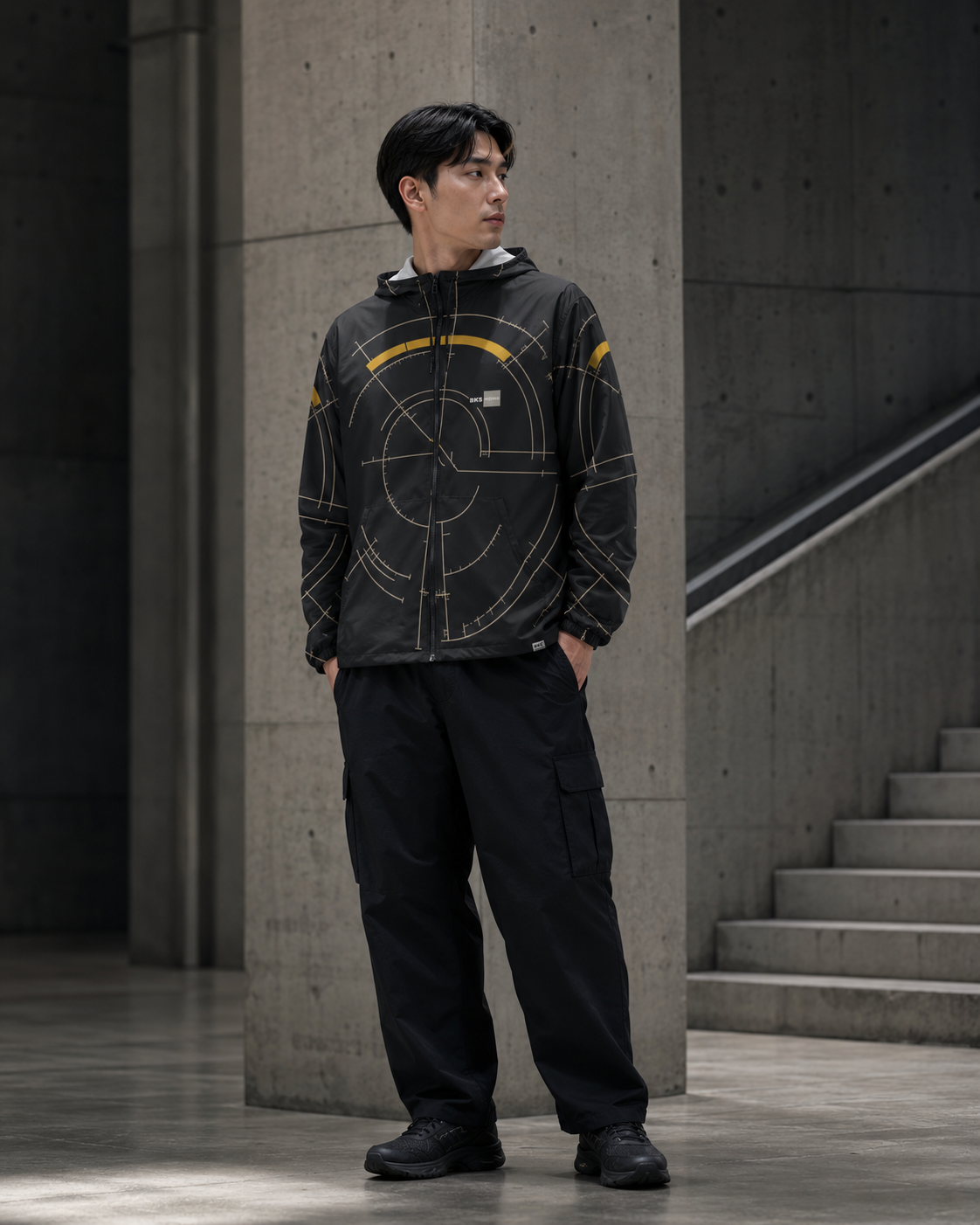BKS Hours Arc Windbreaker on model, brutalist concrete staircase setting