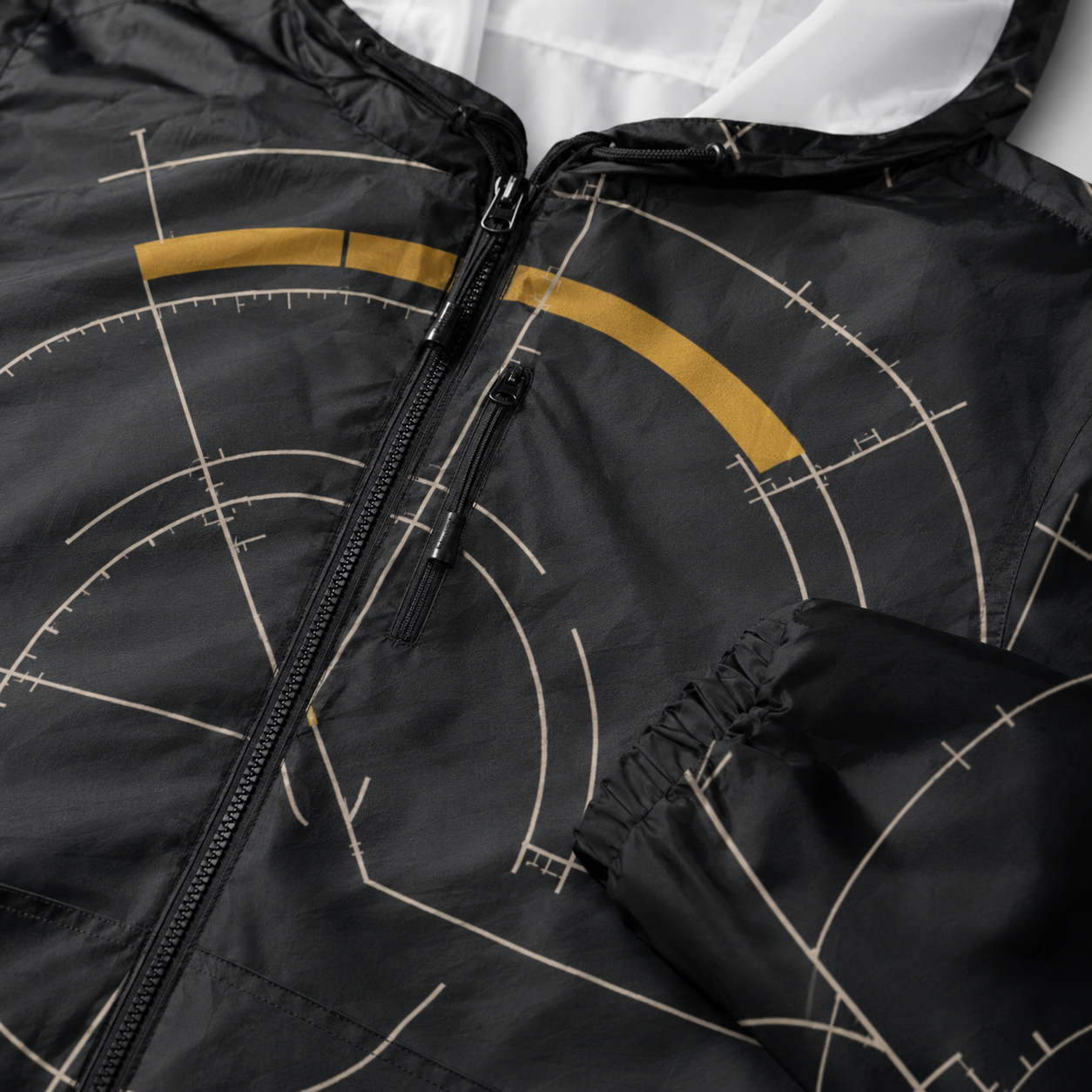 BKS Hours Arc Windbreaker detail — gold arc accent and silver construction marks on onyx