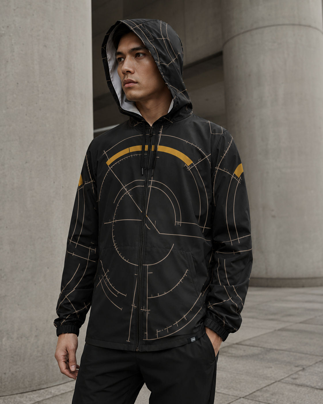 BKS Hours Arc Windbreaker lifestyle — hood up, brutalist columns